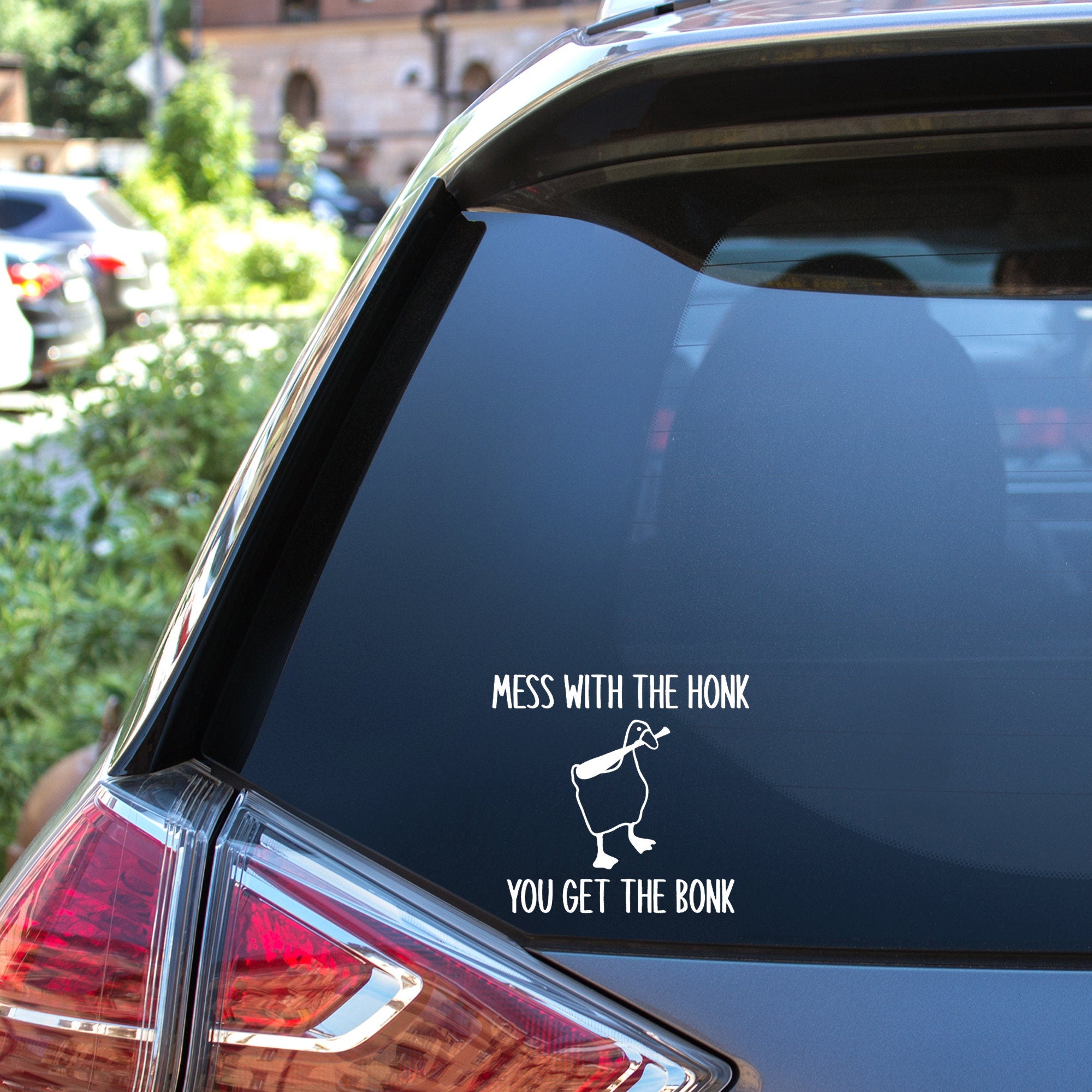 Car window with a humorous decal that reads "mess with the honk you get the bonk" with a picture of a goose holding a bat in their mouth.